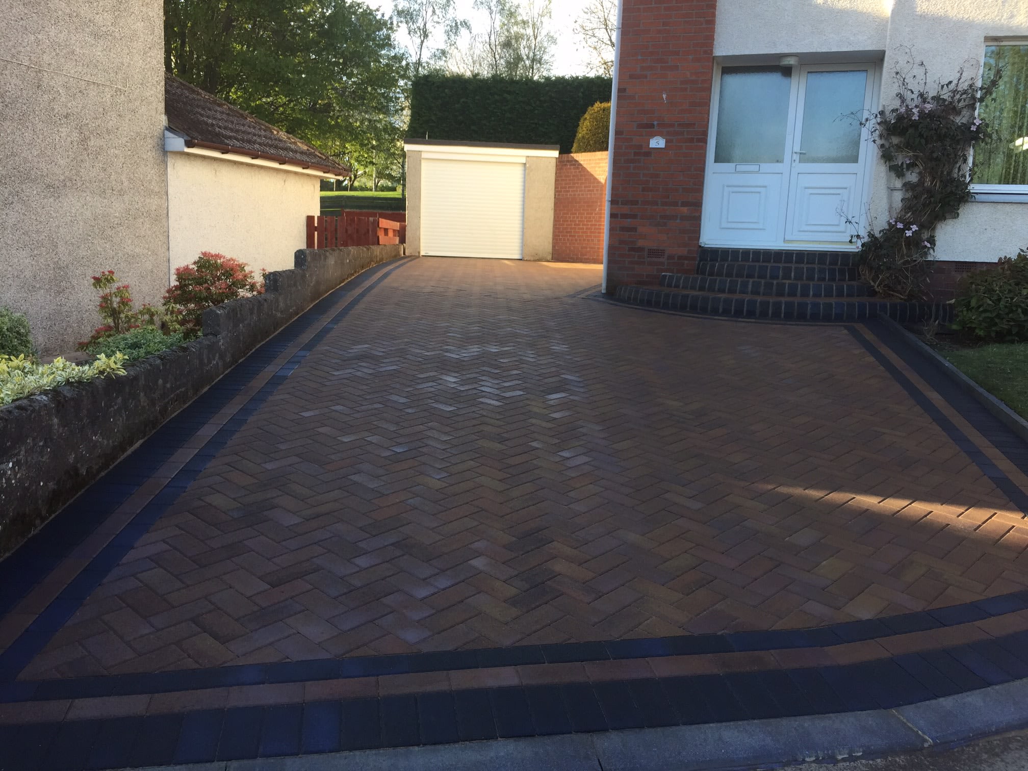 Brindle monoblock driveway with a charcoal double border sweeping to a garage in Dundee